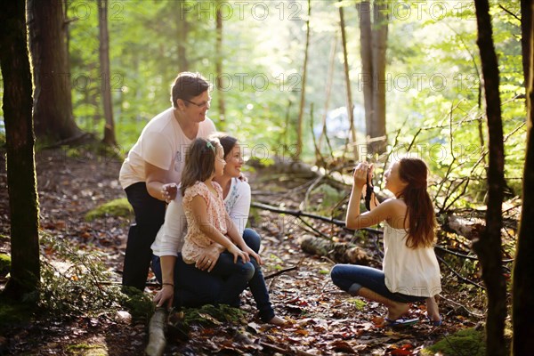 Caucasian girl photographing family in forest