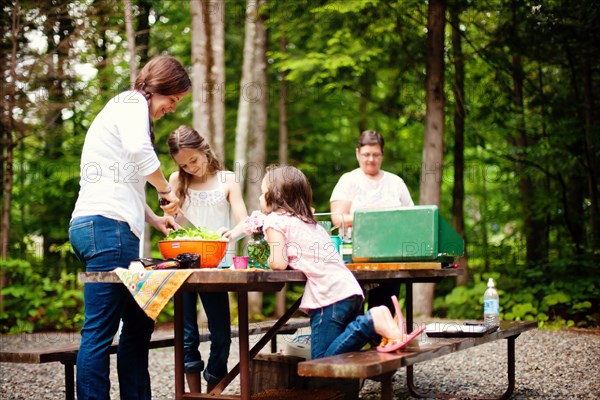 Three generations of Caucasian women cooking at picnic table