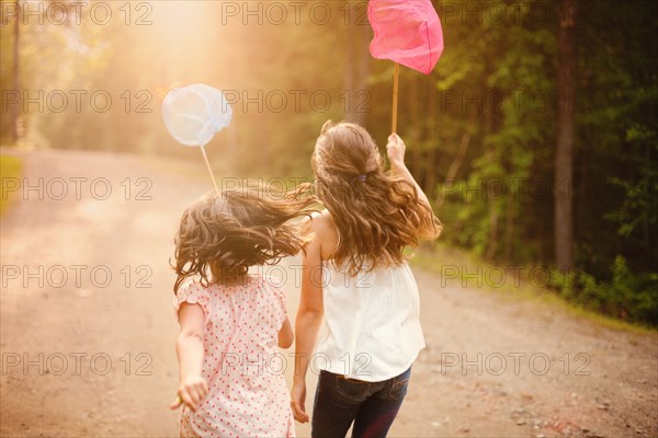 Caucasian girls carrying butterfly nets on dirt road