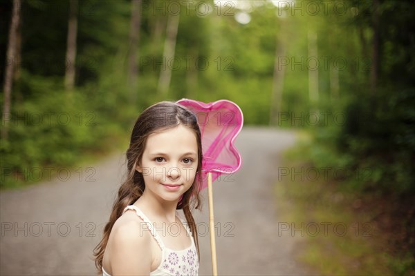 Caucasian girl carrying butterfly net on dirt road