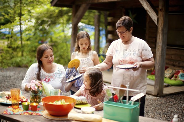 Three generations of Caucasian women cooking outside cabin