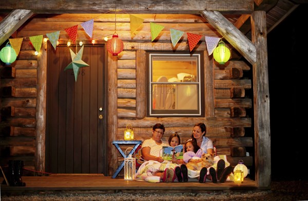 Three generations of Caucasian women reading on cabin porch