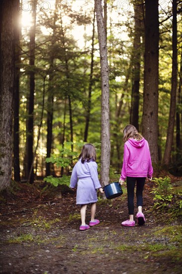 Caucasian girls carrying pot of water in forest