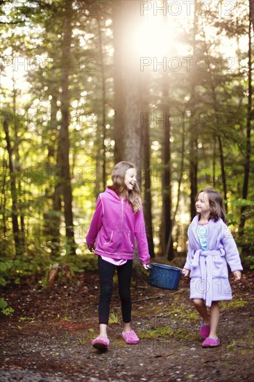 Caucasian girls carrying pot of water in forest