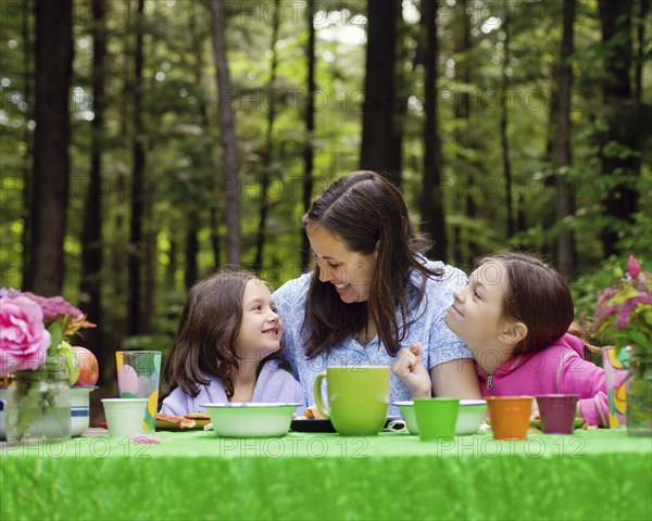 Caucasian mother and daughters sitting at table outdoors