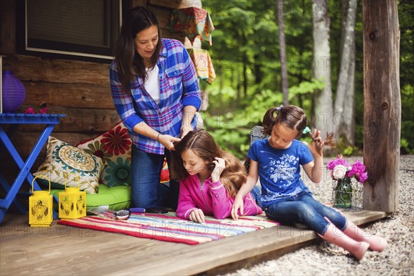 Caucasian mother brushing hair of daughter on porch