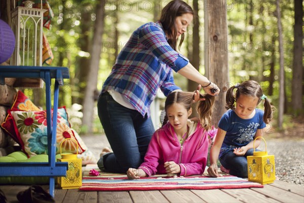 Caucasian mother brushing hair of daughter on porch