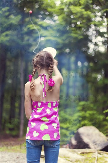 Caucasian girl playing with toy in forest