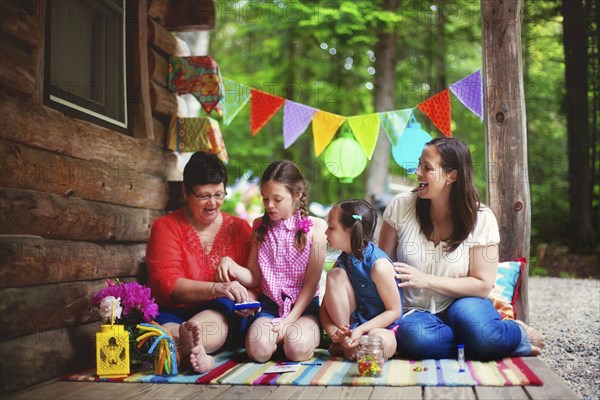 Three generations of Caucasian women playing with toy on cabin porch