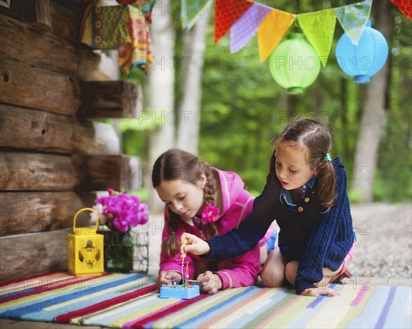 Caucasian girls playing with toy on cabin porch