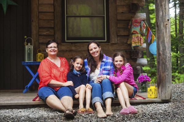 Three generations of Caucasian women smiling on cabin porch