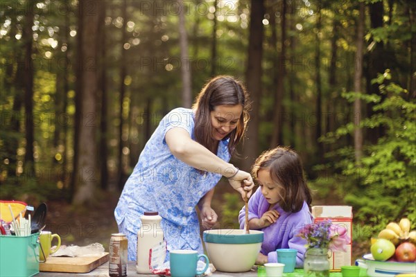 Caucasian mother and daughter cooking in forest