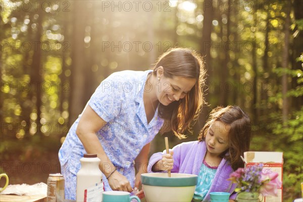 Caucasian mother and daughter cooking in forest