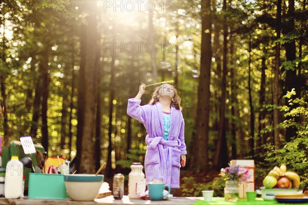 Caucasian girl blowing bubbles in forest