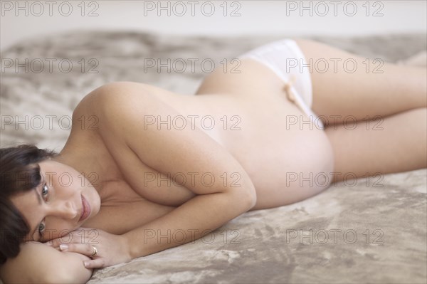 Pregnant Caucasian woman laying on bed