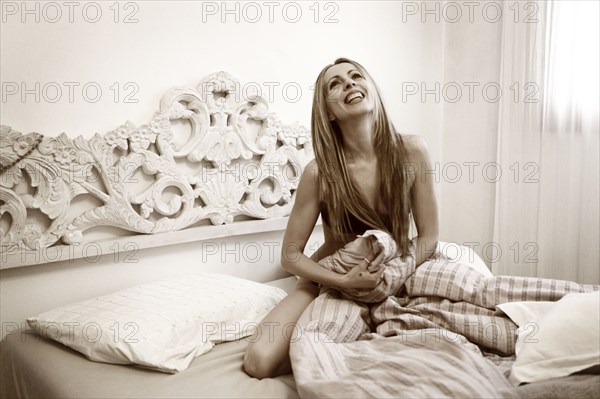 Nude Caucasian woman sitting on bed