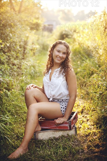 Woman sitting on crates in garden