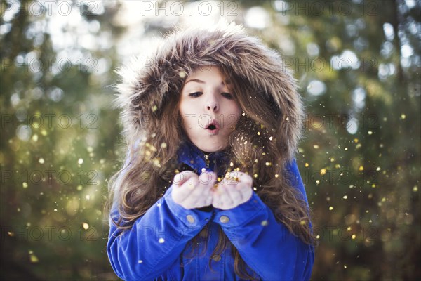 Woman blowing glitter from hands