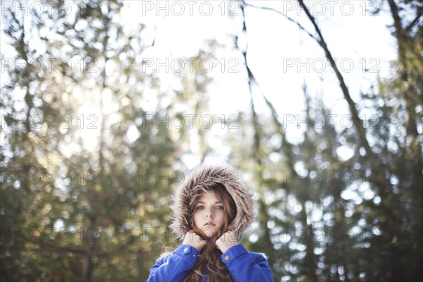 Woman wearing fur hood under trees