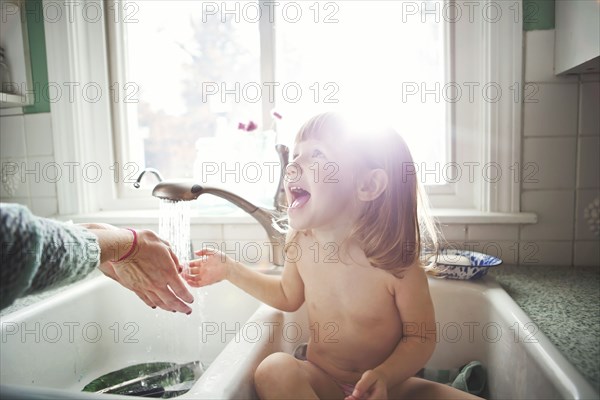 Girl bathing in kitchen sink