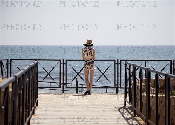 Woman standing on boardwalk overlooking ocean