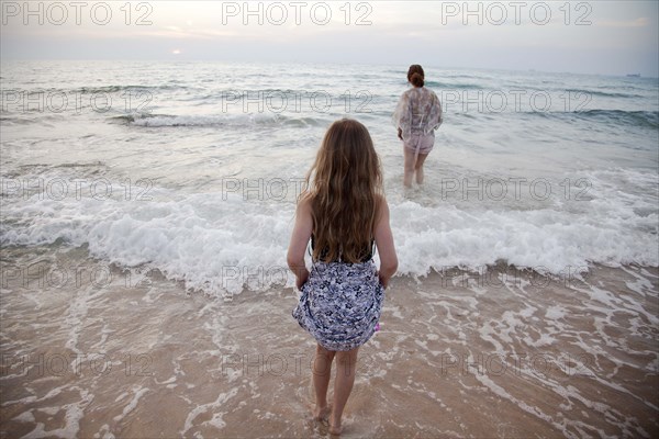 Women walking in ocean waves on beach