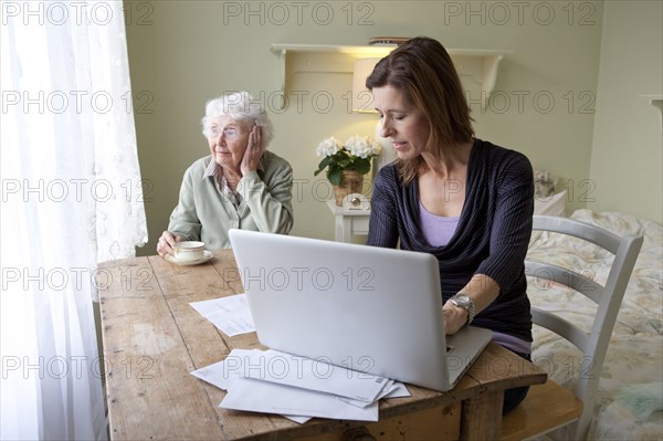 Woman paying bills for elderly mother