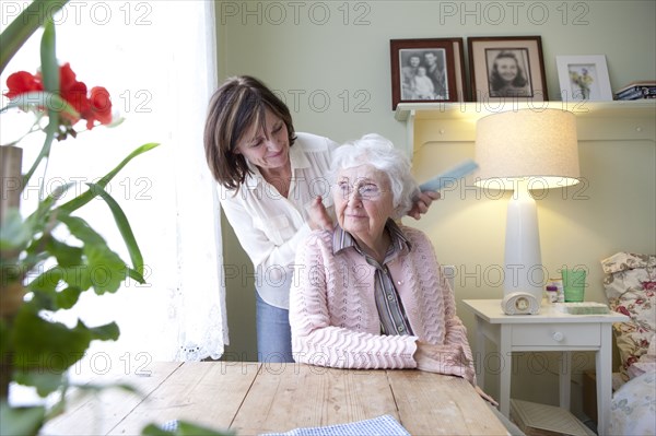 Woman combing hair of elderly mother