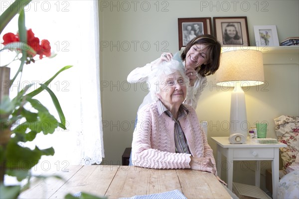 Woman combing hair of elderly mother