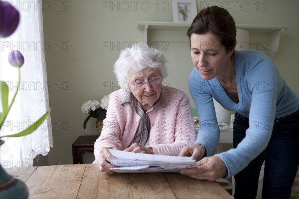 Woman reading to mother at table