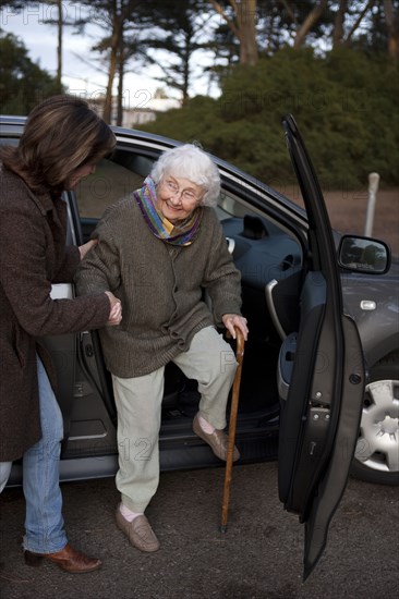 Woman helping mother out of car