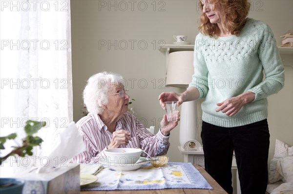Woman giving mother glass of water