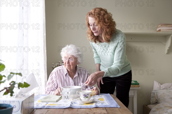 Woman feeding mother at table