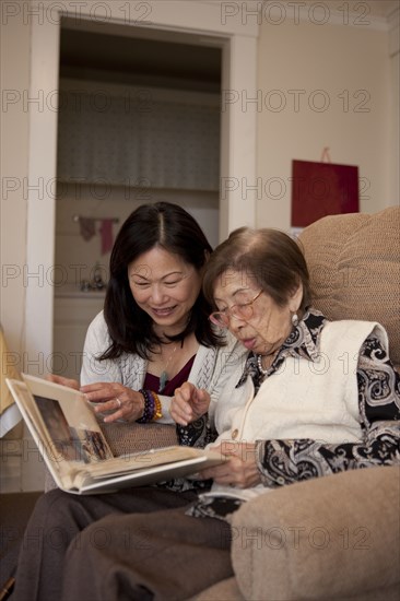 Asian mother and daughter looking at photo album