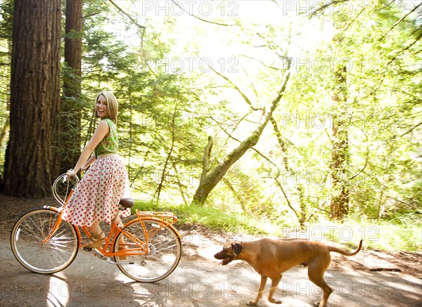 Mixed race woman riding bicycle with dog