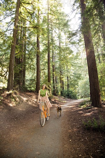 Mixed race woman riding bicycle with dog