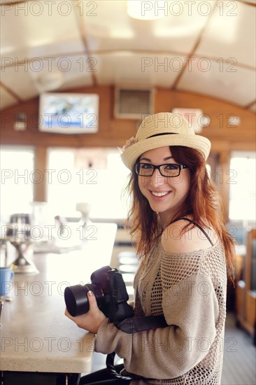 Caucasian woman holding camera in restaurant