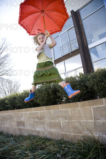 Caucasian girl jumping with umbrella