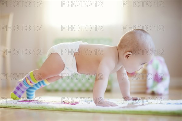 Mixed race baby girl playing on floor