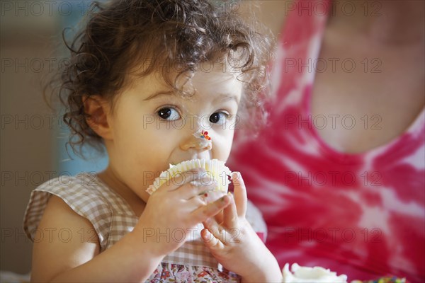 Messy baby girl eating cupcake