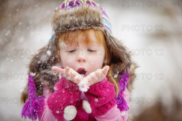 Caucasian girl blowing handful of snow