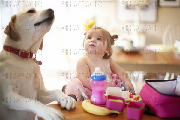 Caucasian girl and dog eating at table