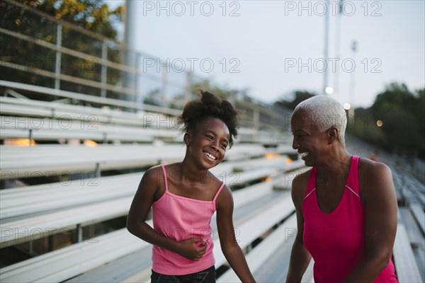 Grandmother and granddaughter standing on bleachers