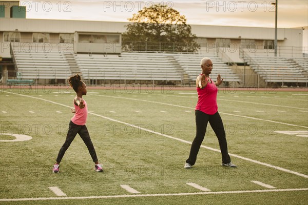 Grandmother and granddaughter exercising on football field
