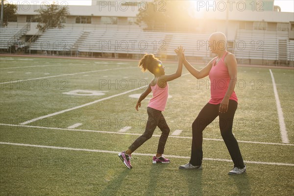 Grandmother and granddaughter high-fiving on football field