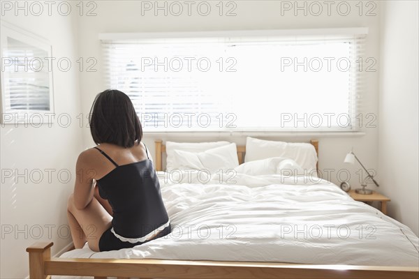 Hispanic woman sitting on bed