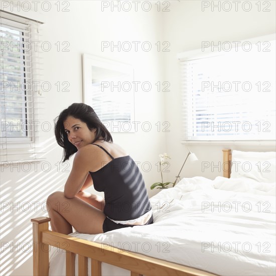 Hispanic woman sitting on bed