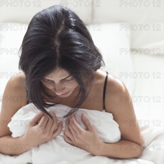 Hispanic woman in bed looking down