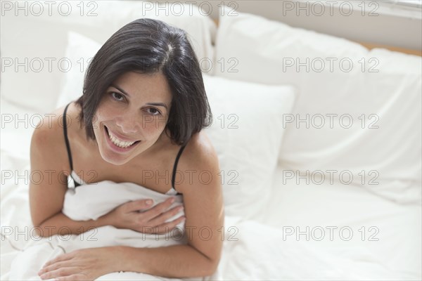 Smiling Hispanic sitting in bed