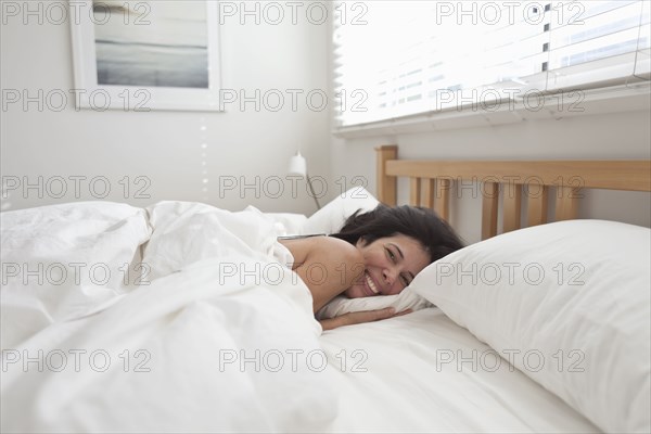 Smiling Hispanic woman laying in bed